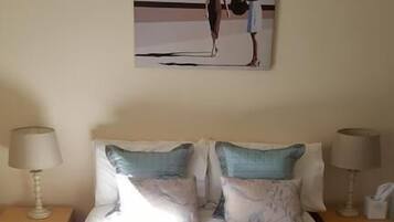 A hotel room with a bed, two nightstands, two lamps, and a painting on the wall.