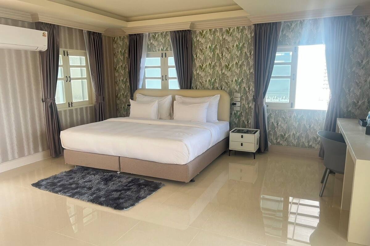 A modern bedroom with a large bed, a desk, and a chair.