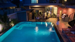 A swimming pool with a tiled edge, surrounded by lounge chairs and a covered seating area.