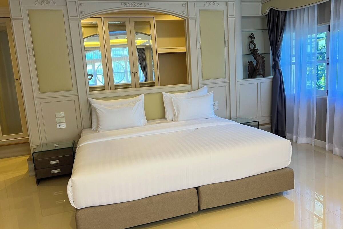 A large bed with a headboard, a nightstand, and a mirror above it.