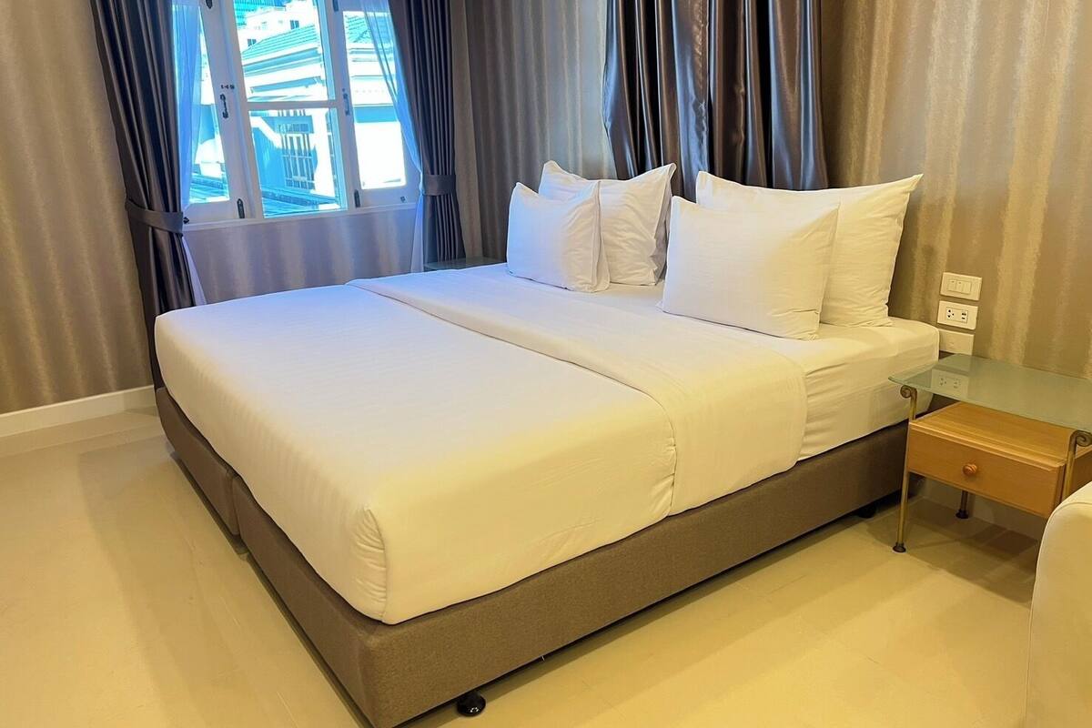 A neatly made bed with white linens in a hotel room.