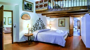 Un dormitorio con cama, dos lámparas de noche, cabecero de madera, un cuadro enmarcado y vistas a un balcón.