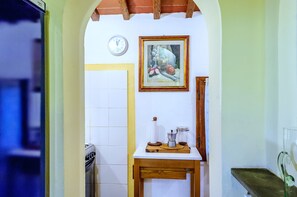 Une cuisine avec une table en bois, une horloge et un tableau encadré.