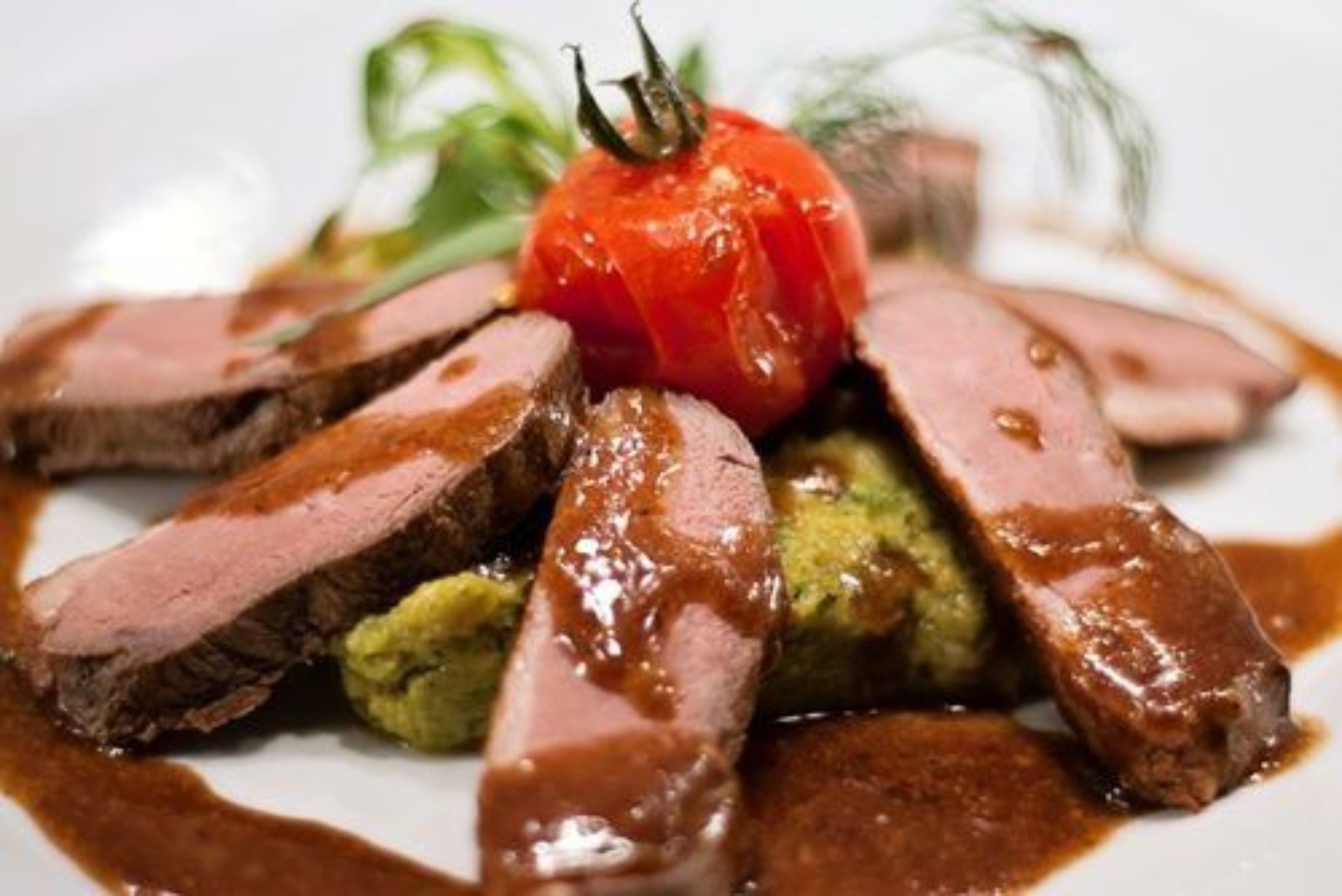 Une assiette de nourriture contenant des tranches de viande et un légume rouge.