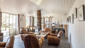 A spacious room with leather sofas, a large wooden tree trunk, and framed pictures on the wall. - Hôtel Ile de Ré (Le Bois-Plage-en-Re)