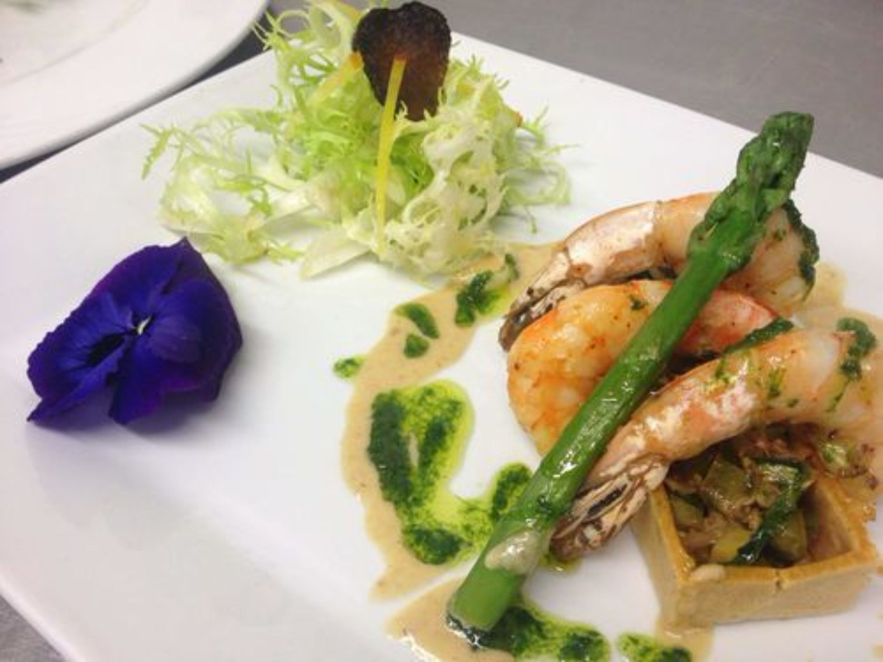 A plate of food with shrimp, asparagus, and a small salad.