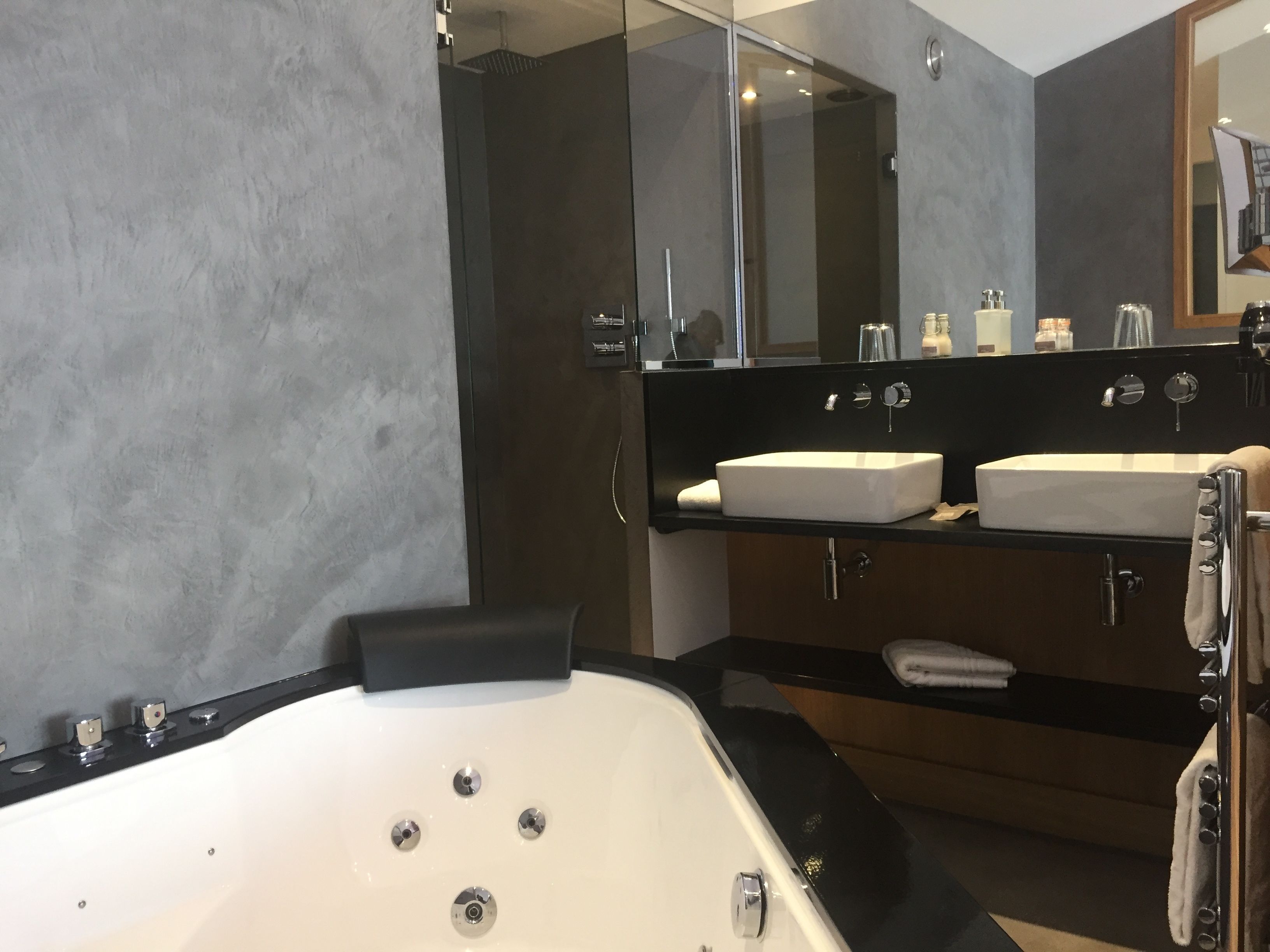 A modern bathroom with a large bathtub, two sinks, and a glass shower enclosure.