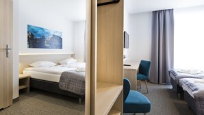 Una habitación de hotel con cama, escritorio, silla y televisión.