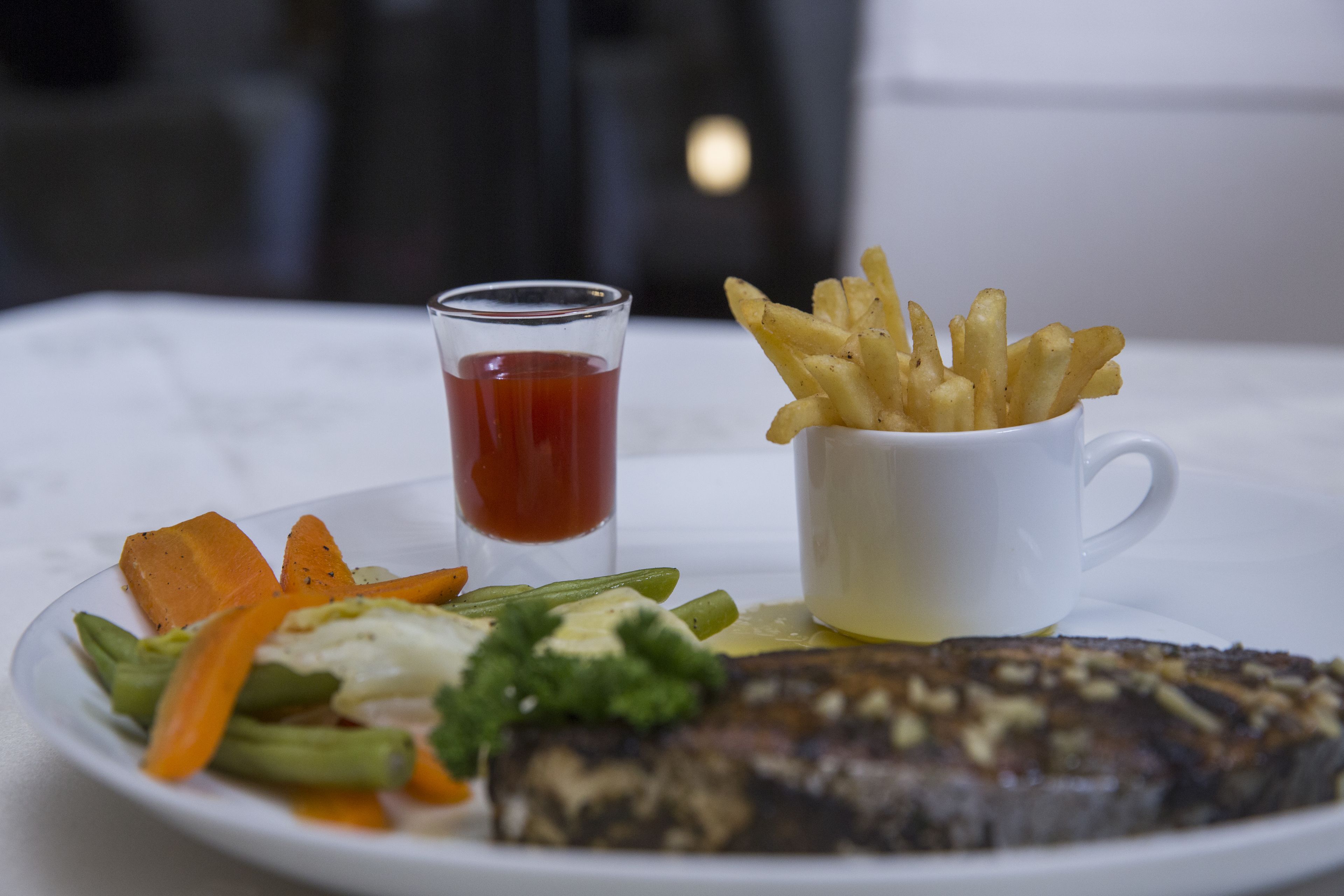 Une assiette avec du poisson, des légumes et une portion de frites.