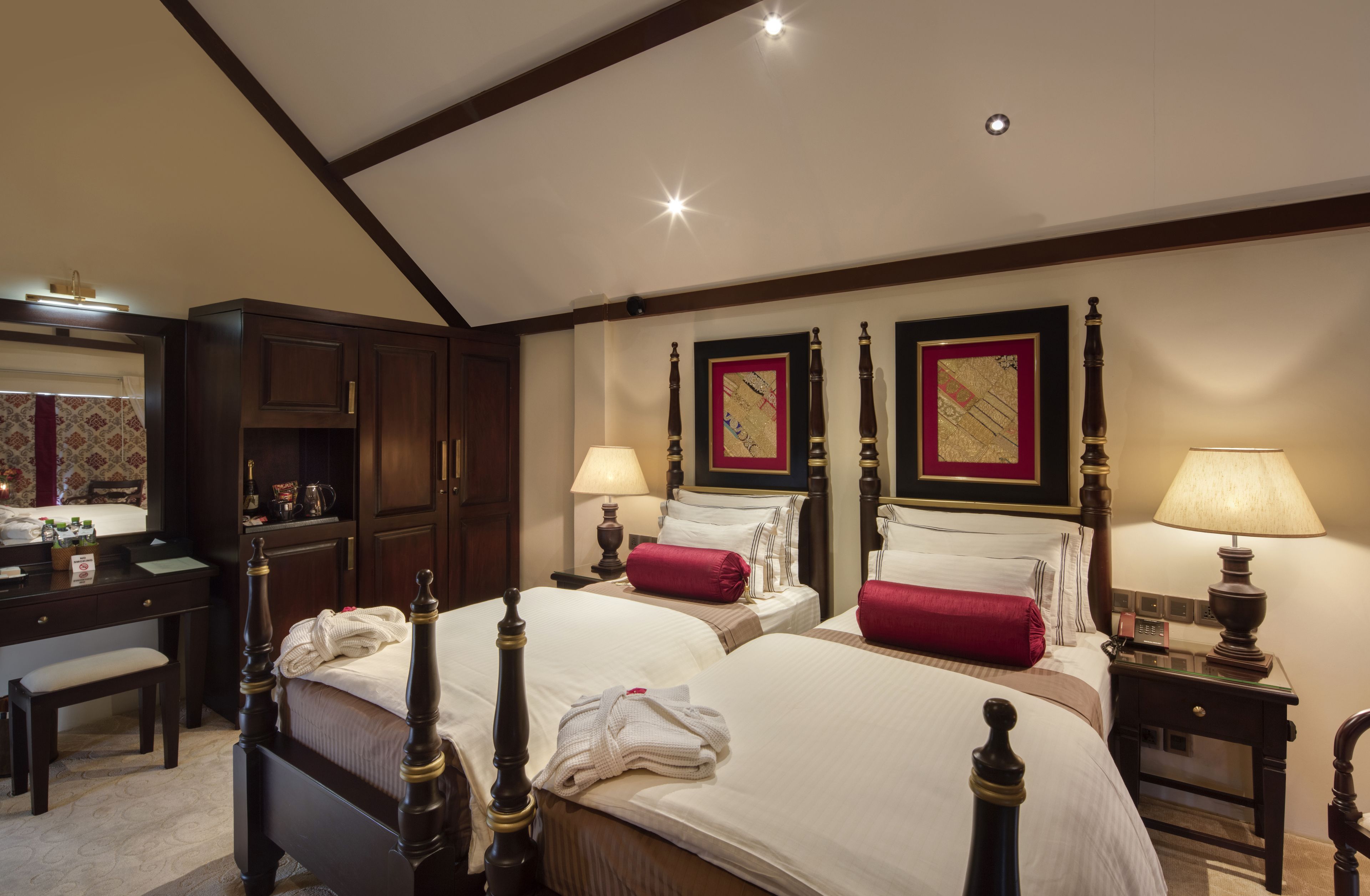 A hotel room with two beds, a desk, and a chair.