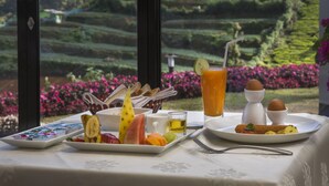 Ein Tisch mit Frühstücksleckereien, einem Getränk und einem Blick auf terrassenförmig angelegte Felder.