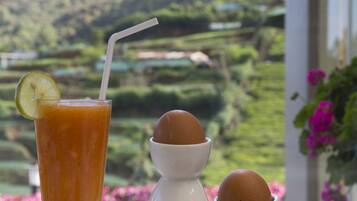 A plate with food and a drink, a window with a view of green hills.