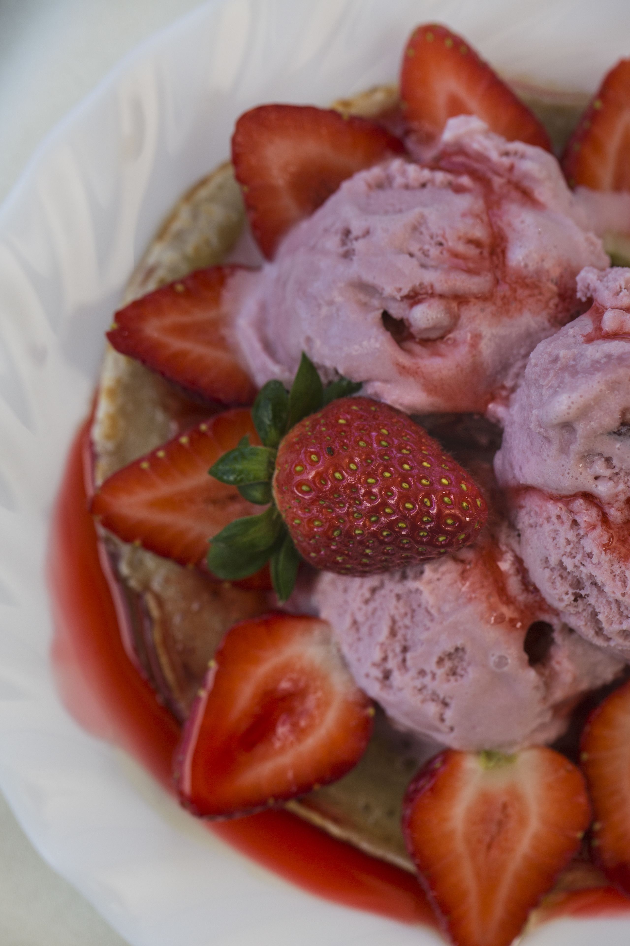 A bowl of ice cream with strawberries on top.