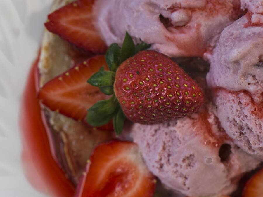 A bowl of ice cream with strawberries on top.