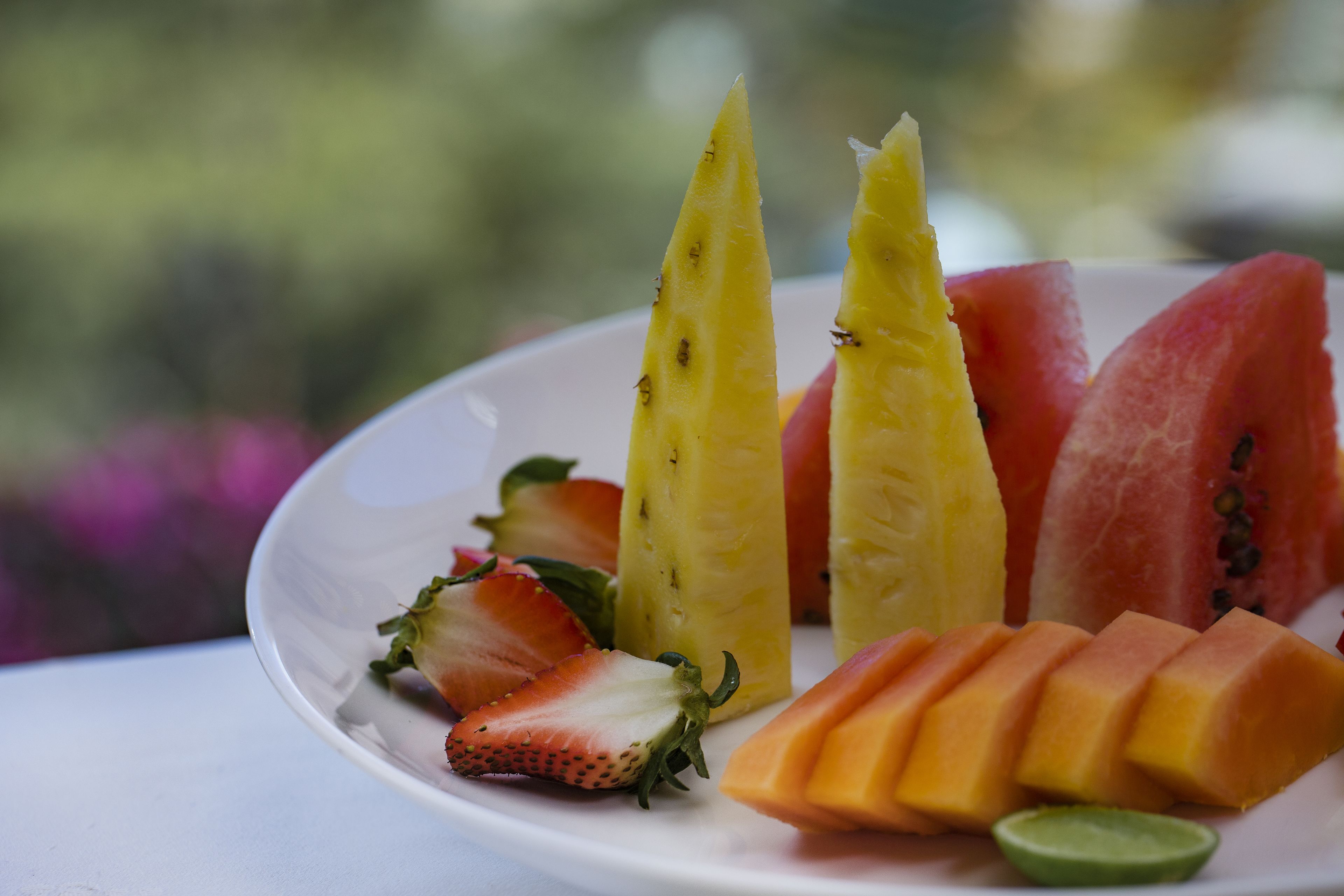 A plate of sliced fruits including watermelon, pineapple, strawberries, and mango.