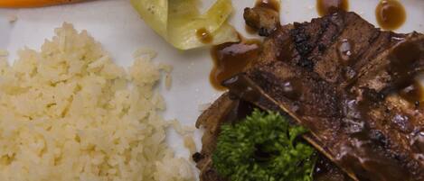 A plate with a beef steak, rice, and mixed vegetables including carrots and green beans.