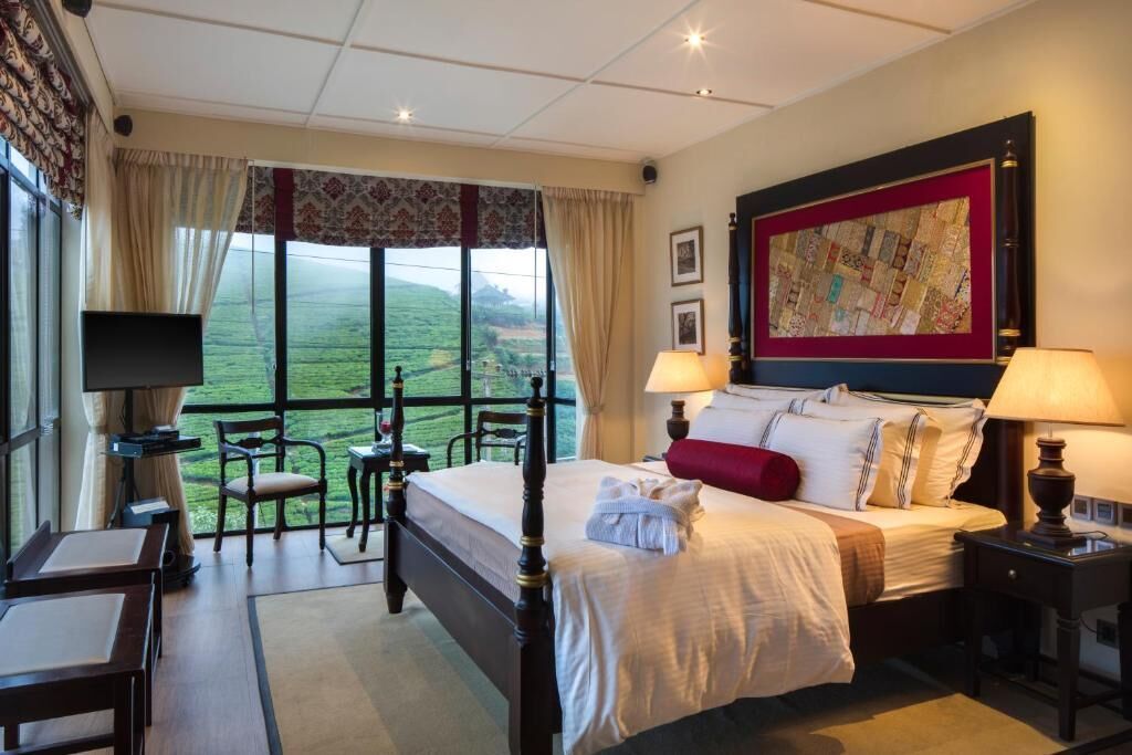 A hotel room with a large bed, two bedside tables, a TV, and a view of the countryside.