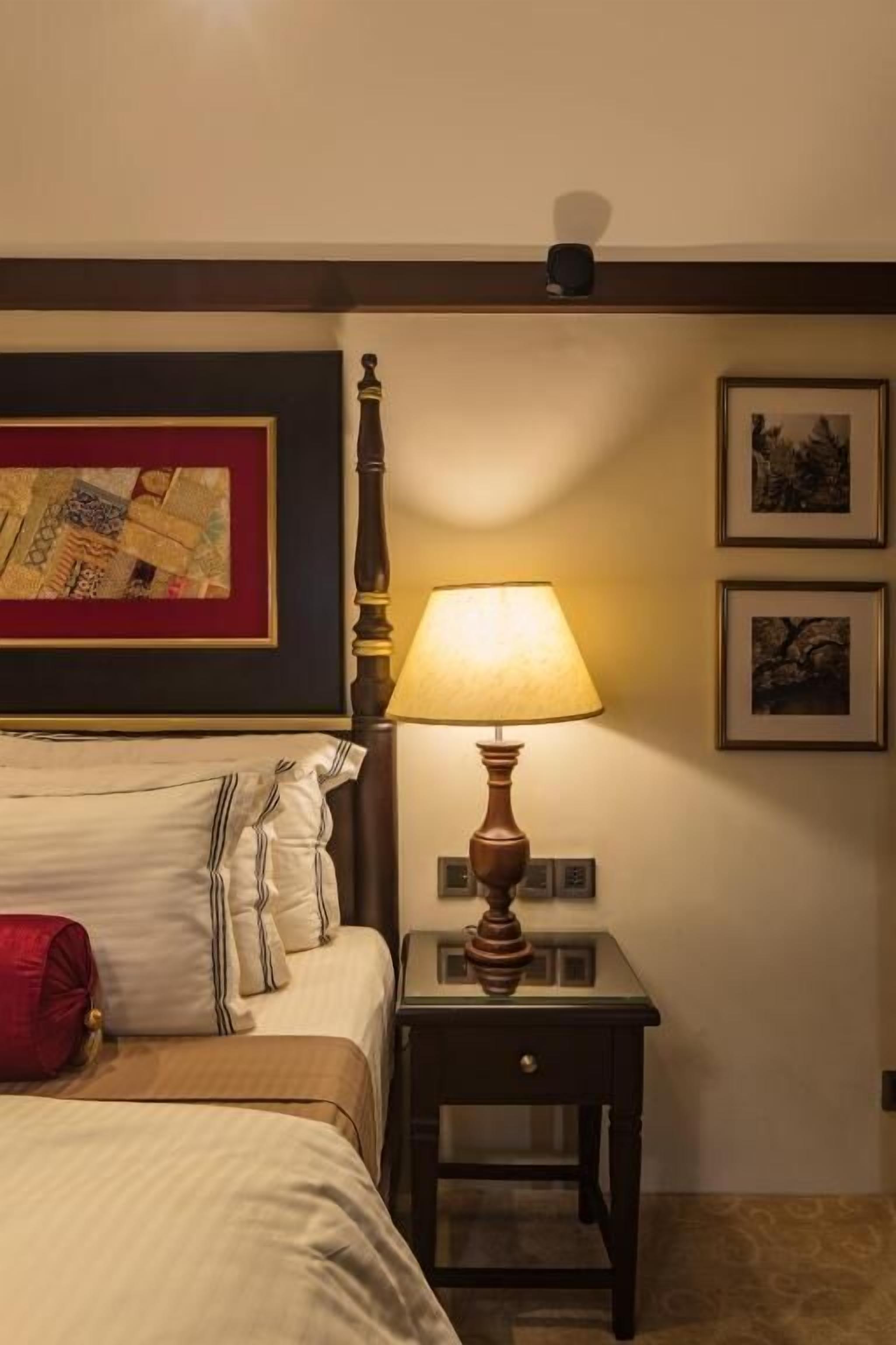 Een hotelkamer met een bed, een nachtkastje met een lamp en een wanddecoratie.