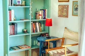 A room with a bookshelf filled with books, a small table with a lamp, and a chair. - Santo Stefano Penthouse (Florence)