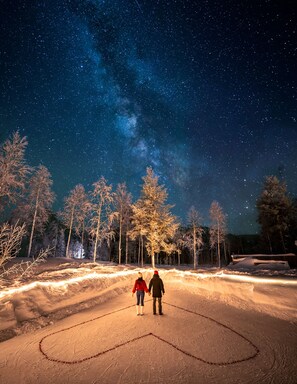 Two people standing in a snowy outdoor area with a starry night sky.