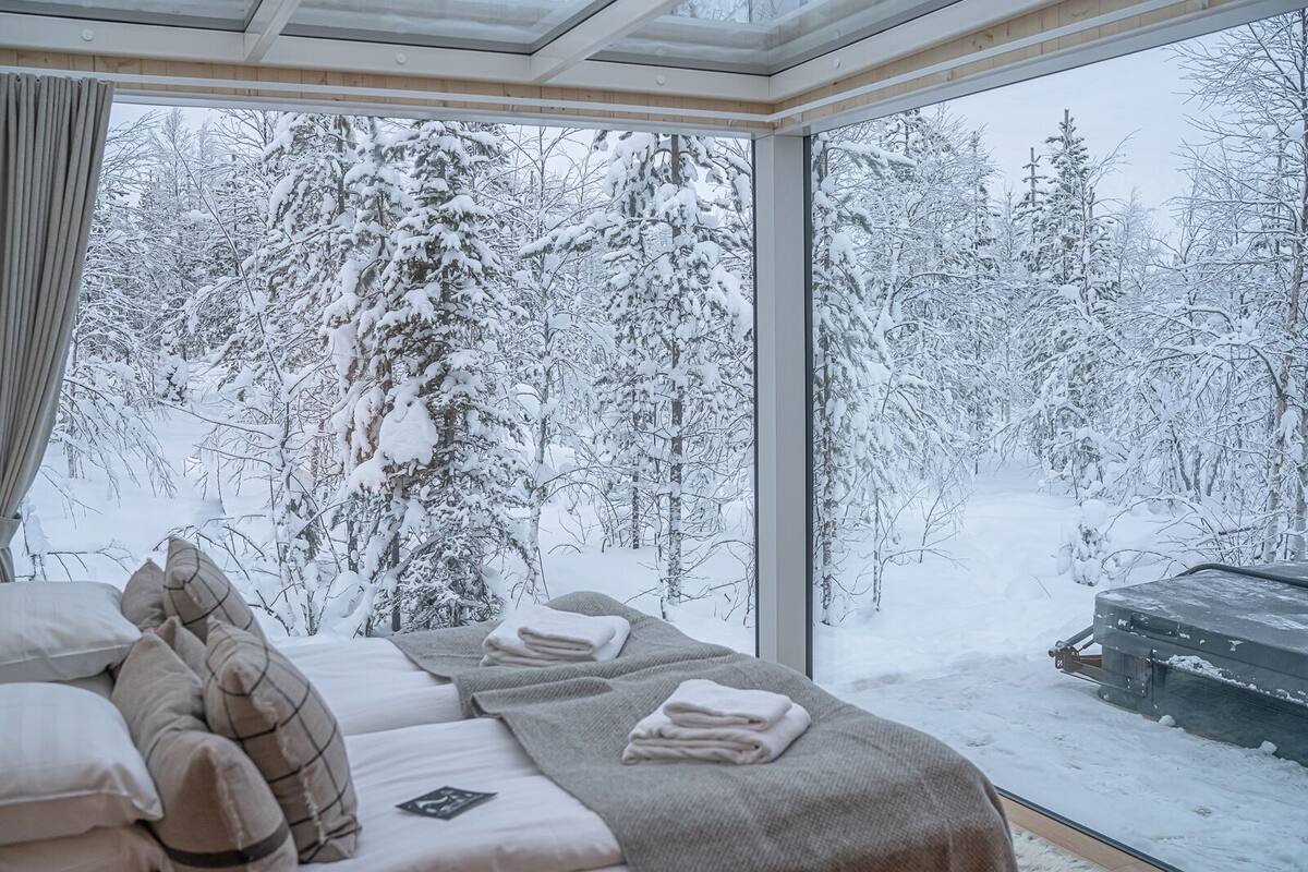 Huone, jossa on suuri ikkuna, josta avautuu näkymä lumiseen metsään.