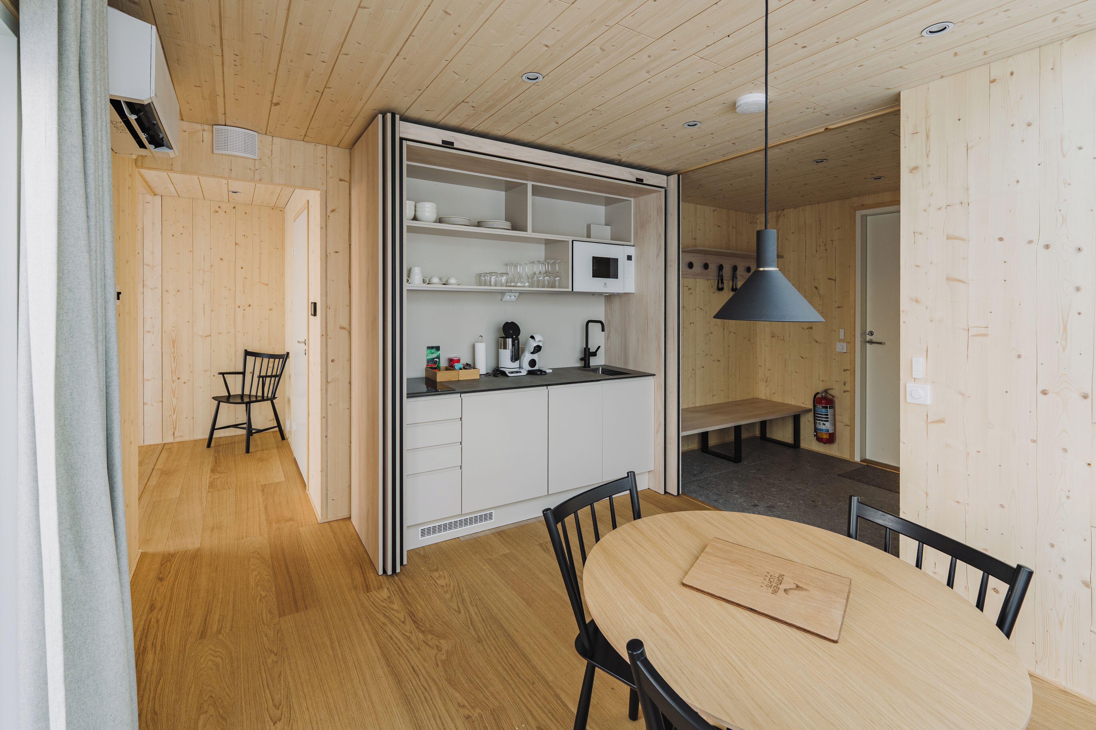 A compact kitchen with white cabinets, a dining table, and a bench.