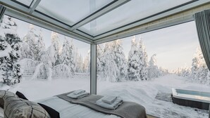 Ein modernes Zimmer mit einem großen Panoramafenster, einem Bett mit ordentlich gefalteten Handtüchern und einer Whirlwanne im Freien.