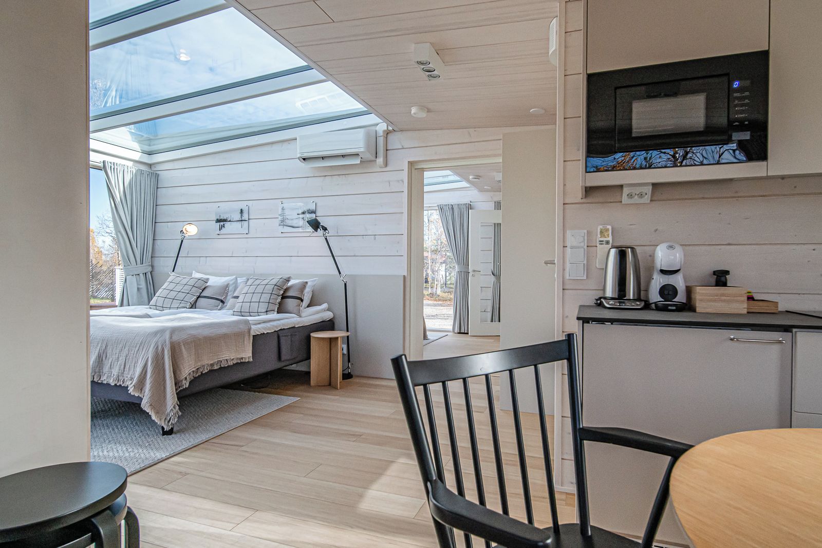 Un espace de vie moderne et compact comprenant un lit, un coin repas et une kitchenette.