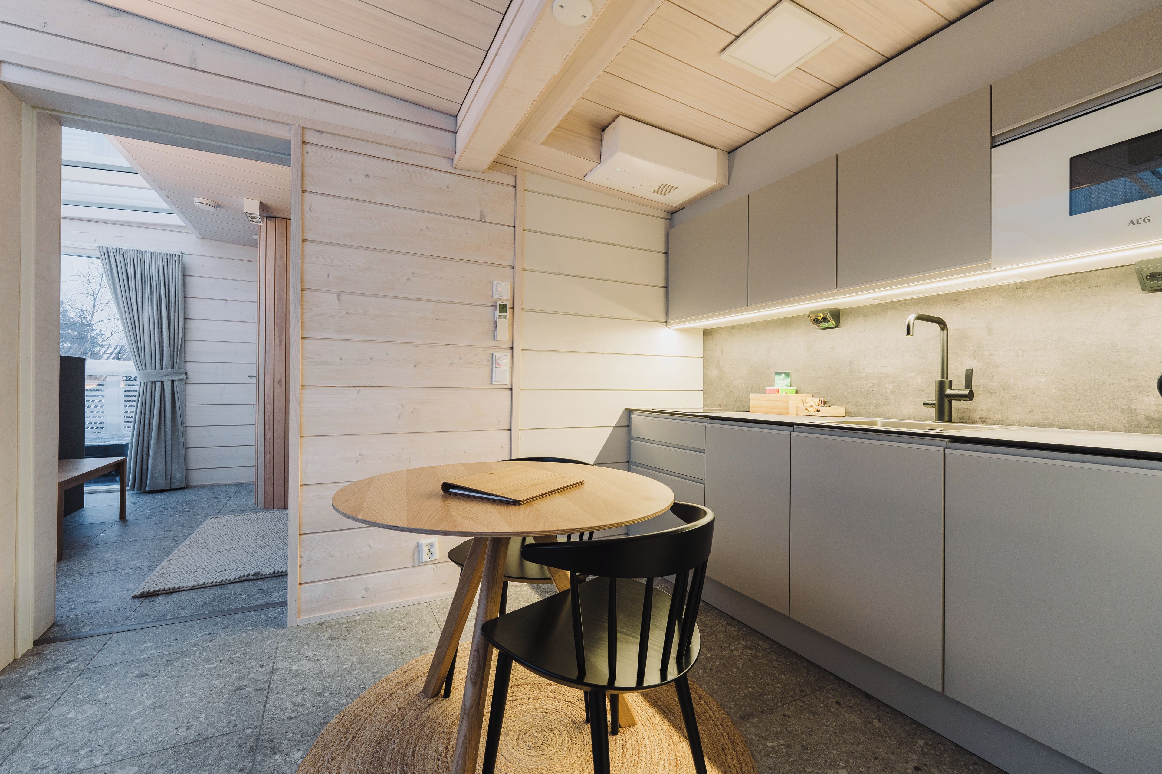 A modern kitchen with a round table, black chairs, and a built-in oven.
