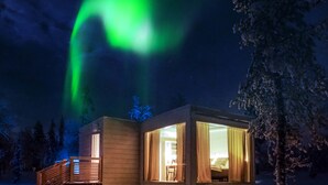Eine Holzhütte mit großen Fenstern und einer sichtbaren Terrassenfläche.