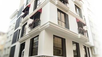 A multi-story building with balconies, a storefront, and potted plants.