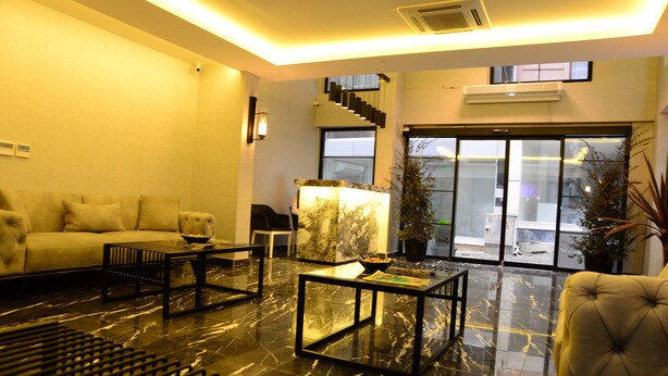 A modern living room with a sofa, coffee table, and a chair. There is a staircase leading to an upper level, and a large window with a view. - Gardenya Suit Hotel (Trabzon)
