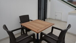 A small outdoor balcony with a wooden table and four wicker chairs. - Gardenya Suit Hotel (Trabzon)