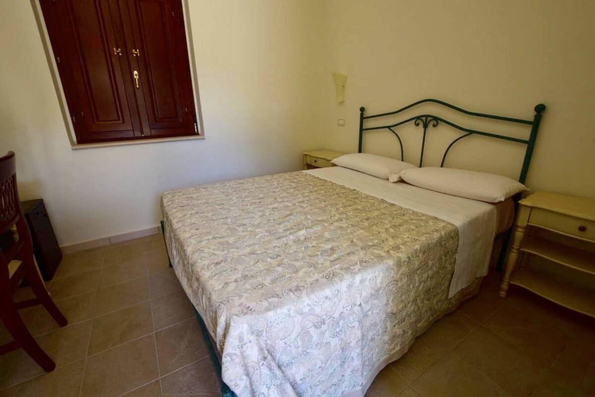 Une chambre à coucher comprenant un lit, une table de chevet, une chaise et une armoire.