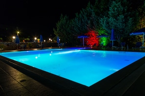 Een buitenzwembad, parasols bij het zwembad en ligstoelen