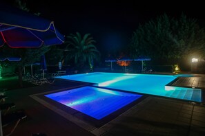 Una piscina al aire libre, sombrillas, sillones reclinables de piscina