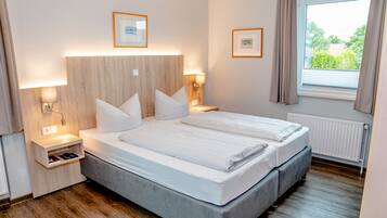 Una camera d'albergo moderna con un letto matrimoniale, comodini, lampade a parete e quadri incorniciati.