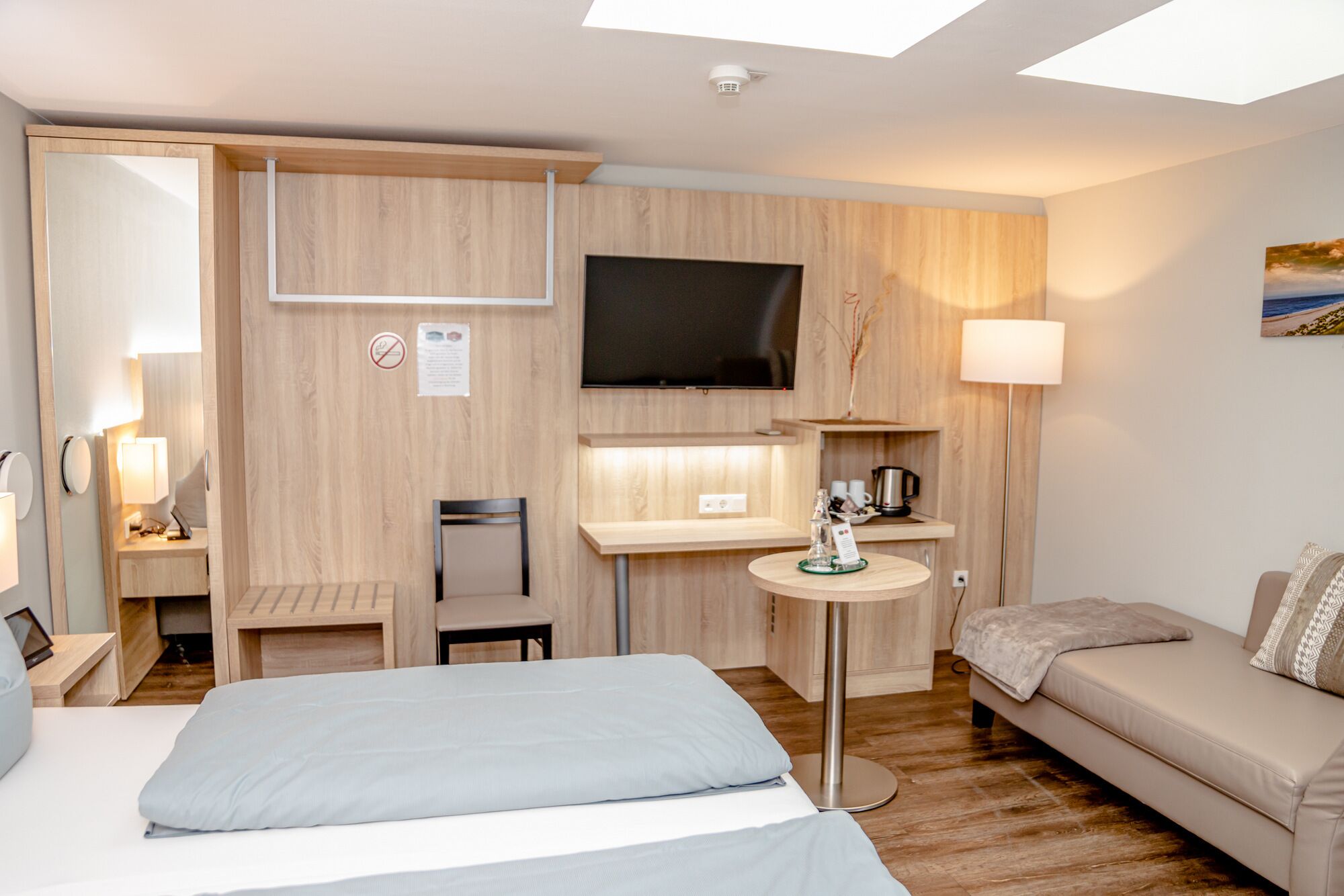 A hotel room with a bed, a sofa, a TV, a desk, and a chair.