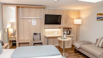 Une chambre d’hôtel avec un lit, un canapé, une télévision, un bureau et une chaise.