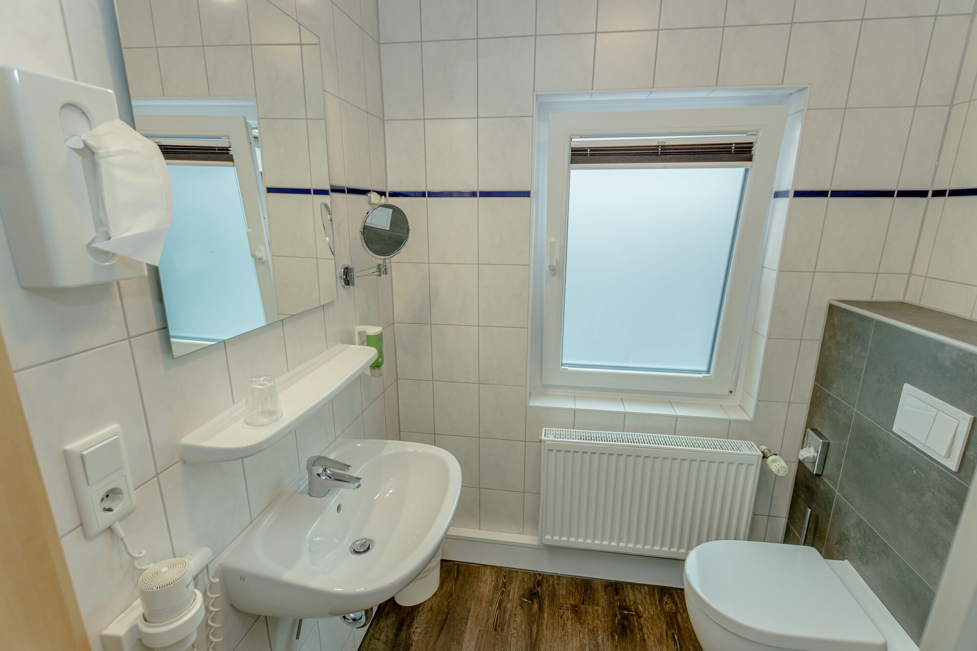 Un baño con lavamanos, espejo, inodoro y ventana con vistas.