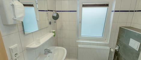 Un baño con lavamanos, espejo, inodoro y ventana con vistas.