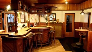 A bar area with wooden bar stools, a counter, and a small round table. - Hotel Herbers & RestaurantLeon (Sudbrookmerland)
