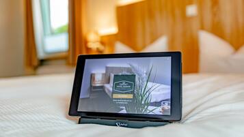 Una tableta mostrando una habitación de hotel con cama, almohadas y mesita de noche.