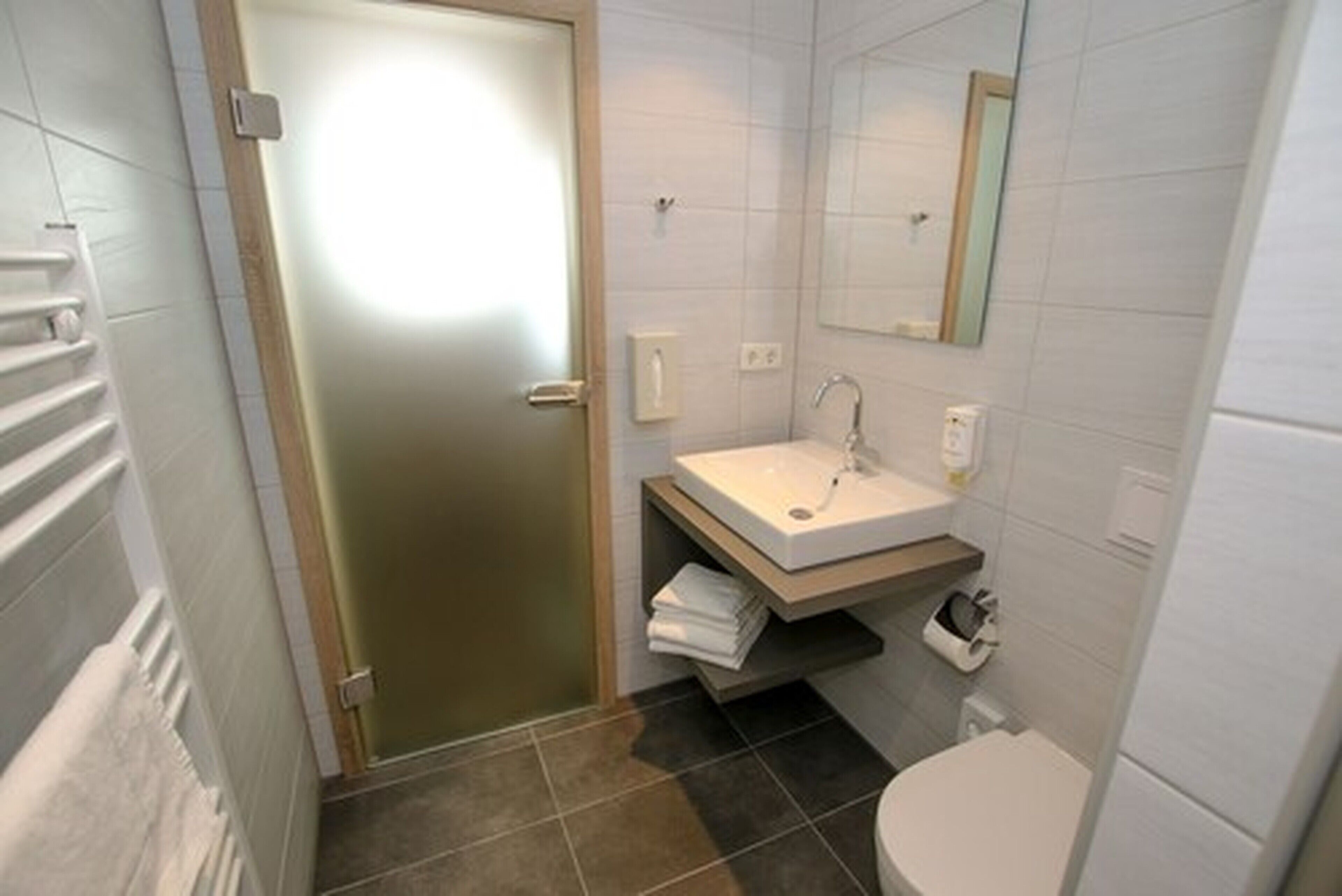 A bathroom with a white sink, a mirror, and a toilet.