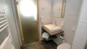 A bathroom with a white sink, a mirror, and a toilet.