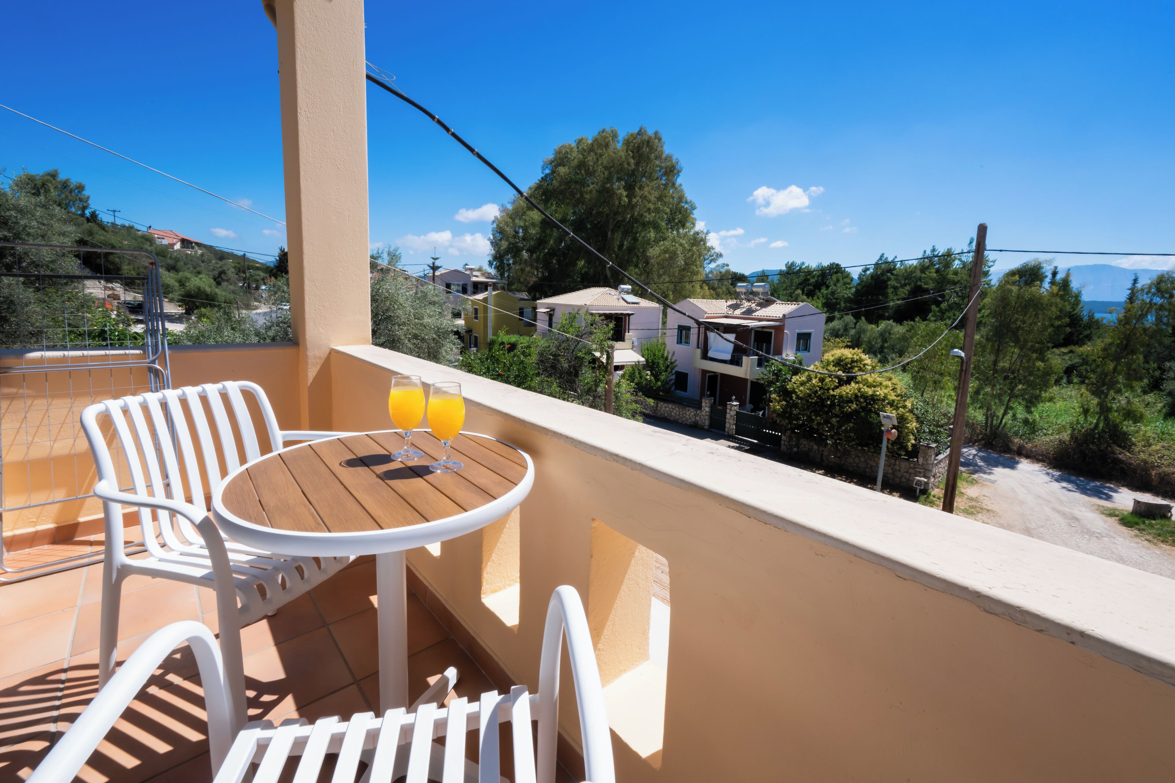 Een balkon met een tafel en stoelen, met uitzicht op een woonwijk met huizen en bomen.