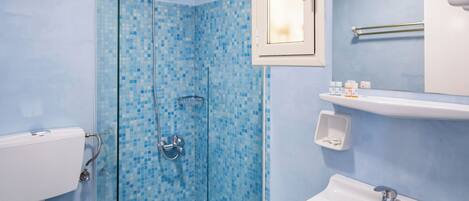 A bathroom with a glass shower enclosure, a white sink, and a toilet.