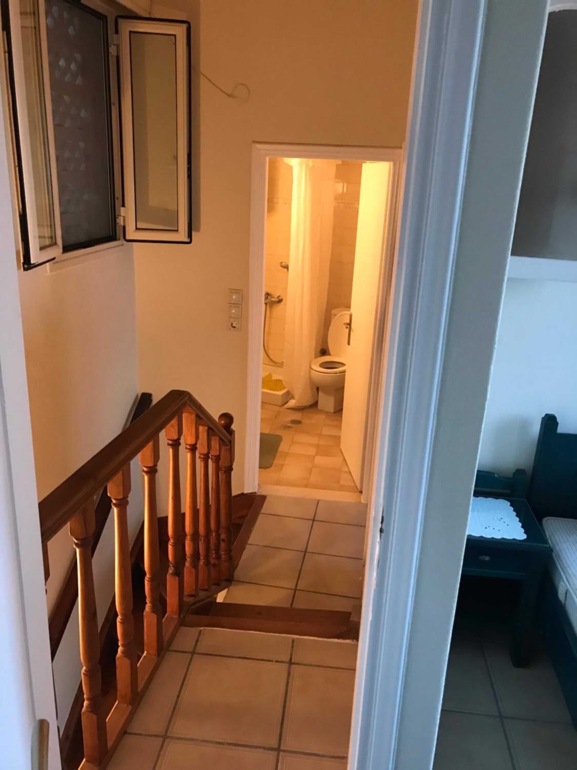 A staircase leading to a bathroom with a toilet and shower.