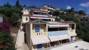 Un immeuble résidentiel à plusieurs étages, doté de balcons, d’un porche avant couvert et situé sur une colline.