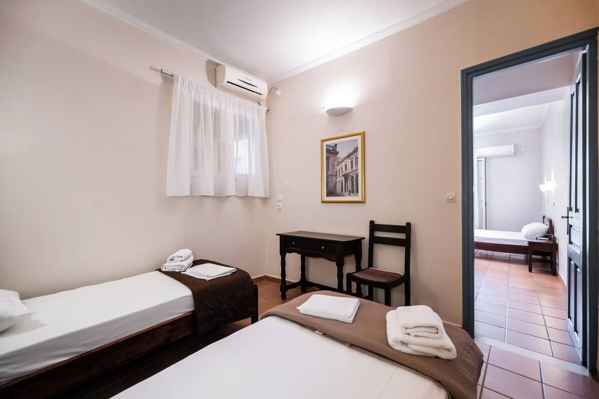 Une chambre d’hôtel avec deux lits, un bureau, une chaise et un tableau au mur.